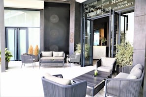 A modern outdoor seating area with sofas and chairs, a coffee table, and potted plants. - Dominium Hotel (Agadir)