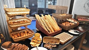 A buffet with various breads, pastries, and a knife on a plate.