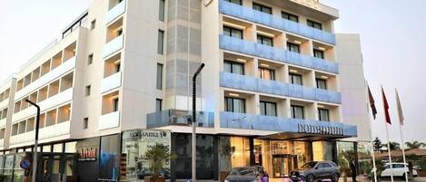 Moderni hotelli, jossa on näyttävä sisäänkäynti, useita kerroksia ja selkeästi näkyvä kyltti, jossa lukee »DOMINUM HOTEL».