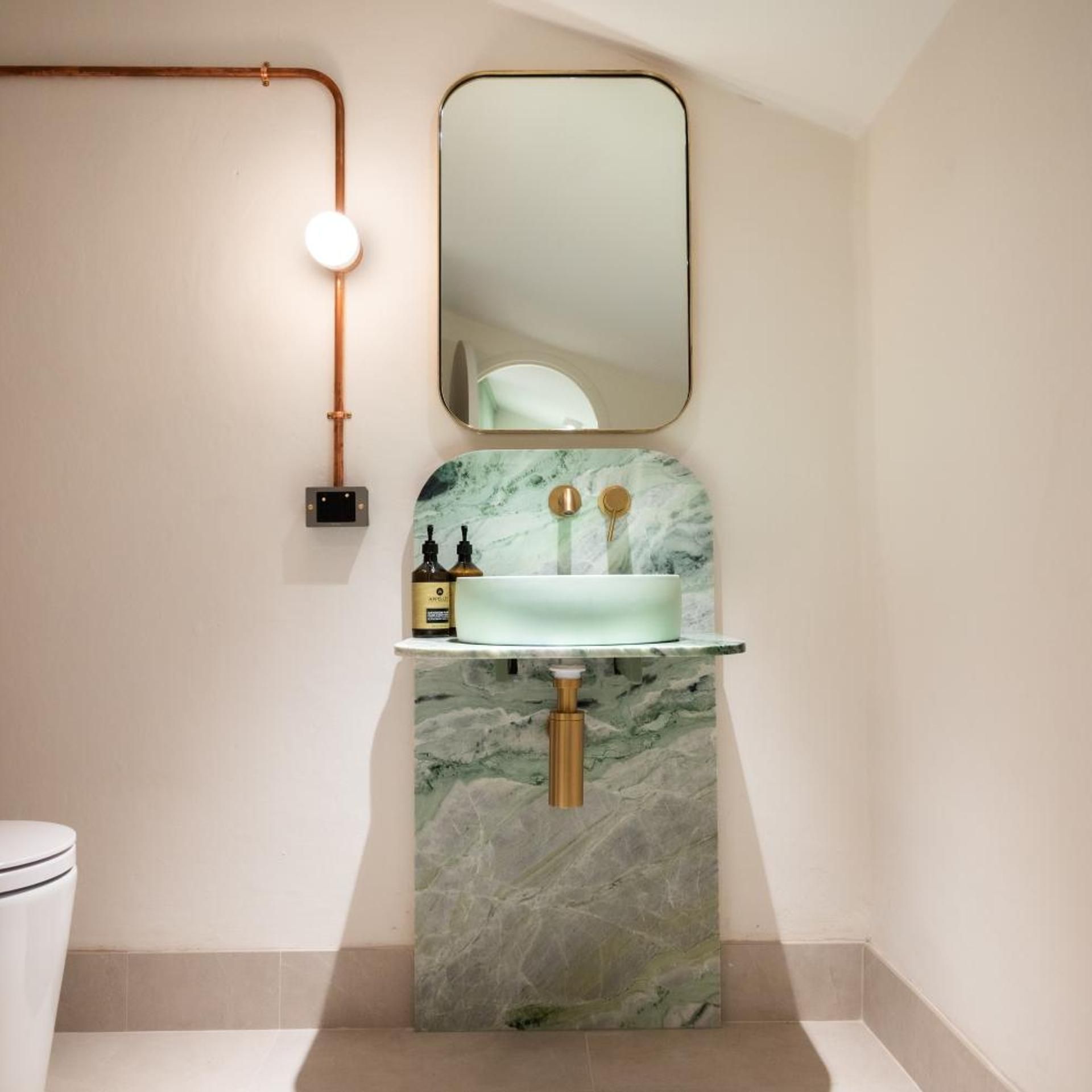 A bathroom with a marble sink, a mirror, and a light fixture.