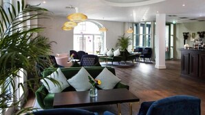 A modern lounge area with green sofas, a coffee table, and a bar area. - The House Hotel Galway (Galway)