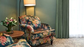 A floral-patterned armchair next to a round wooden table with a vase of flowers. - The House Hotel Galway (Galway)