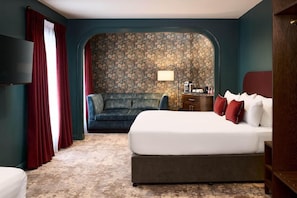 A hotel room with a bed, a sofa, a TV, and a stone-patterned wall. - The House Hotel Galway (Galway)