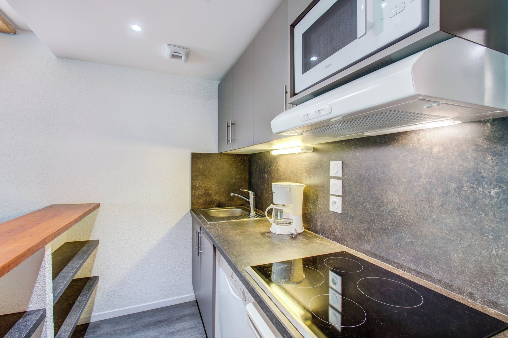 Cocina compacta con microondas, cafetera y estufa.