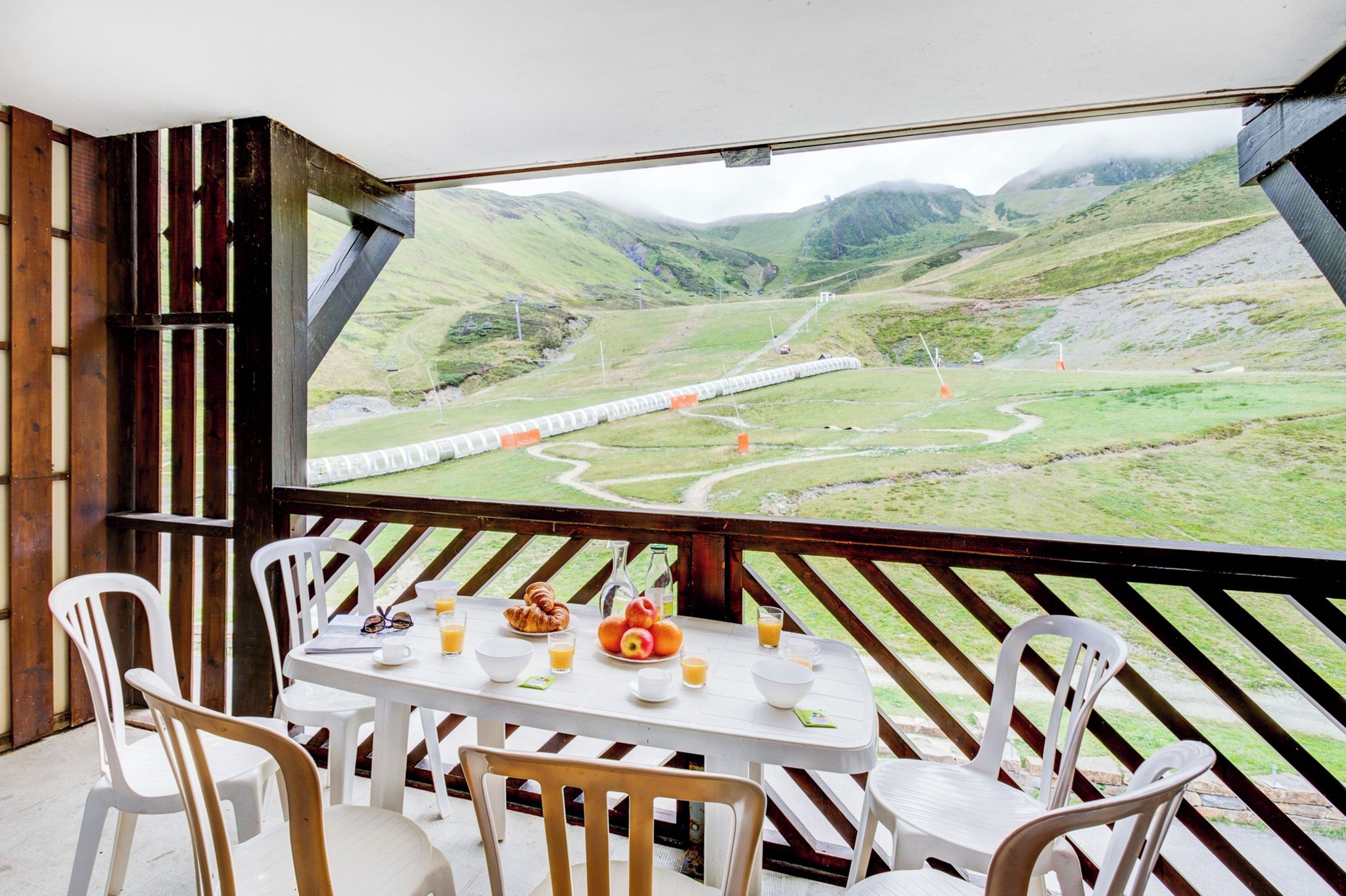 A dining area with a table set for two, a view of a train track, and a mountainous landscape.
