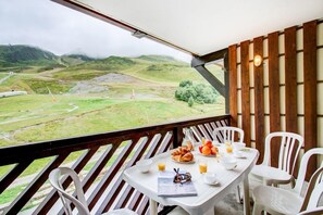 Un coin repas avec une table dressée pour deux personnes, donnant sur un paysage montagneux.