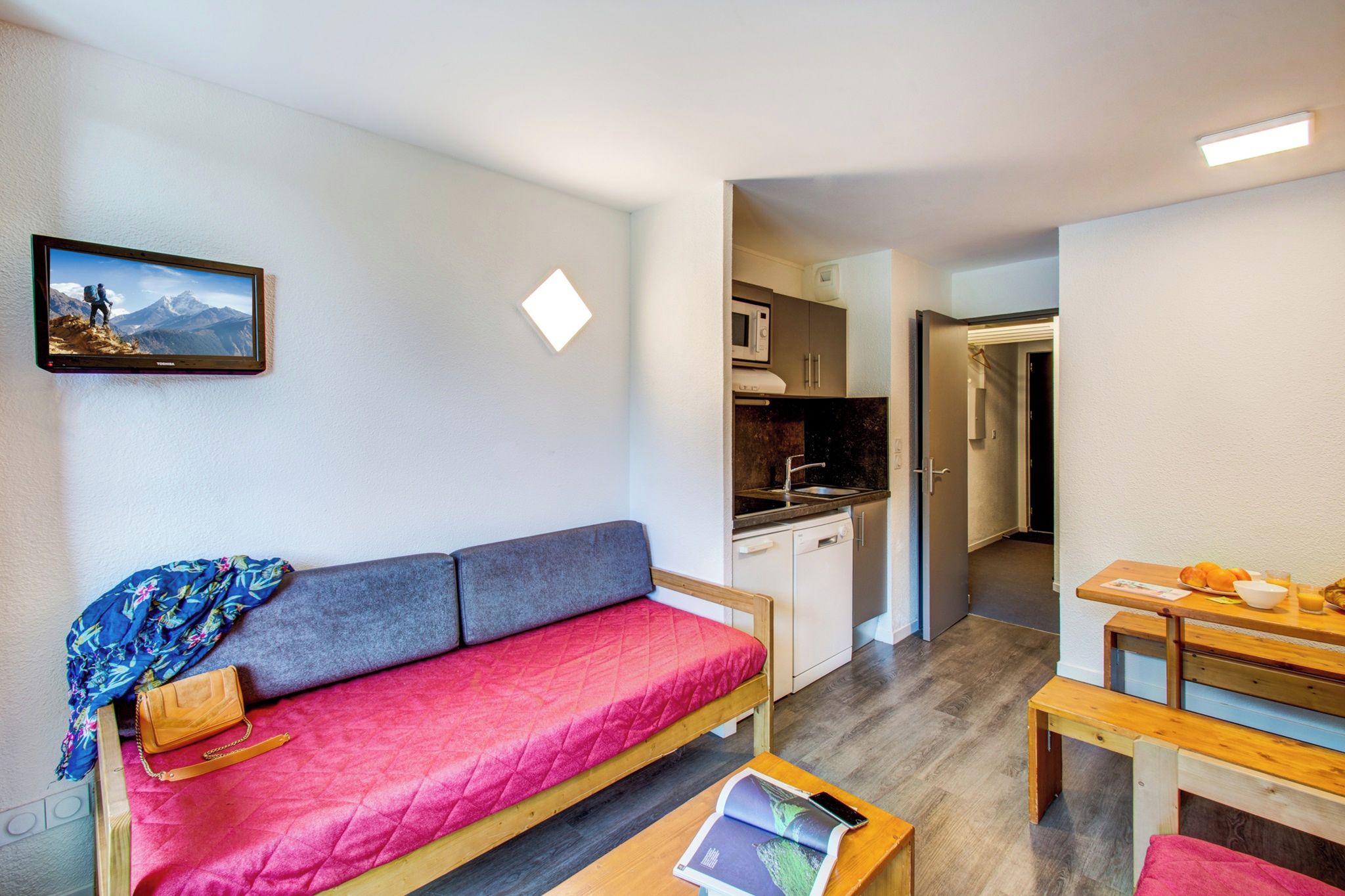 Un espacio habitable compacto con sofá, una pequeña mesa, kitchenette y comedor.