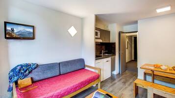 Un espacio habitable compacto con sofá, una pequeña mesa, kitchenette y comedor.
