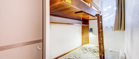 Una cama litera con cabecera de madera, un colchón acolchado y una revista en la cama inferior.