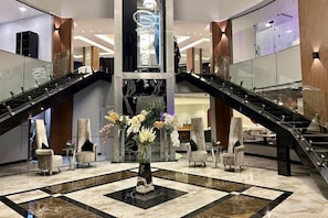 Um saguão com dois elevadores rolantes, um arranjo floral central e áreas de estar.