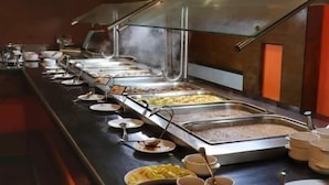 A buffet setup with multiple food stations, including a hot food station and a cold food station, with serving utensils and plates. - XU San Stefano Hotel Alexandria (Alexandria)