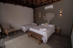 A room with two single beds, a wooden bench, a chair, and a wall-mounted air conditioner. - Santuario Beach Hostel (Cartagena)