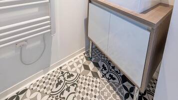 Une salle de bain moderne avec un lavabo blanc, un miroir et des carreaux de sol à motifs.