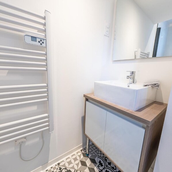 A bathroom with a white sink, mirror, and towel rack. - Le Nid - Appart'hotel Le Gatsby (Saint-Quentin)
