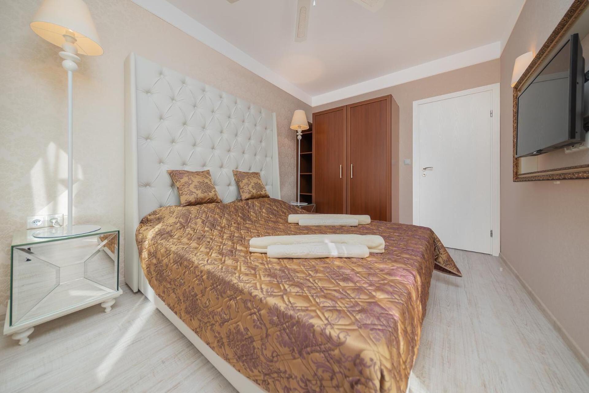Un dormitorio con una cama grande, una mesita de noche, un armario y un espejo en la pared.