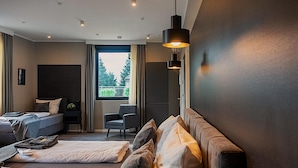 Una habitación de hotel moderna con una cama grande, un sofá, una silla y un televisor.