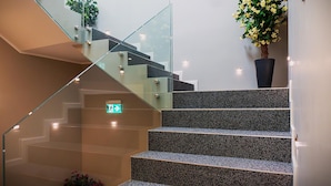 Una escalera moderna con barandillas de vidrio y una planta en maceta.