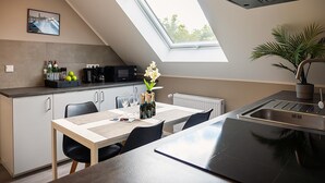 Eine moderne Küche mit Oberlicht, einem Esstisch mit Stühlen, einer Kaffeemaschine und einem Blumentopf.