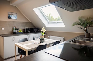 Una cocina moderna con tragaluz, una mesa de comedor con sillas, una cafetera y una planta en maceta.