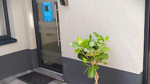 Ein Blumentopf vor einem Gebäude mit einer Tür, auf der 'WASHROOM LAUNDRY' steht, und einem Schild für das 'LiRo Hotel'.