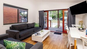 Ein modernes Wohnzimmer mit Sofa, Couchtisch und Essbereich mit Stühlen.