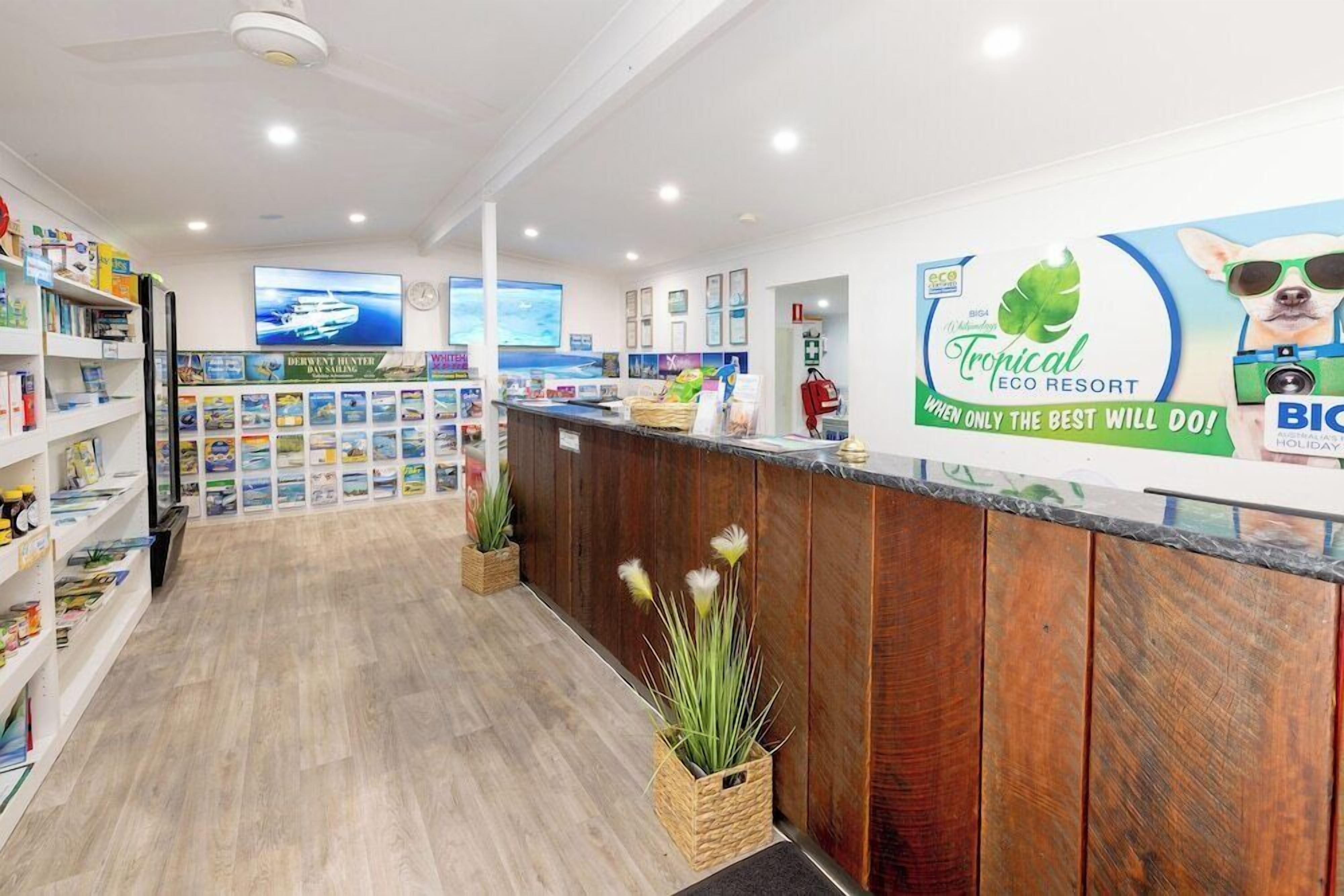 A reception area with a wooden counter, informational posters, and a large screen displaying a boat.