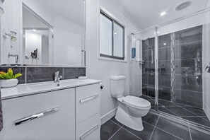 Une salle de bain moderne avec un meuble-lavabo blanc, des toilettes et une douche à parois de verre.