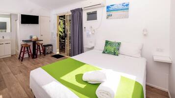 Een hotelkamer met een bed, bureau, televisie en raam met gordijnen.