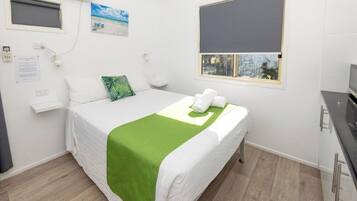 Ein Hotelzimmer mit Bett, einem Fenster mit Blick, einem kleinen Nachttisch und einer Wand-Klimaanlage.