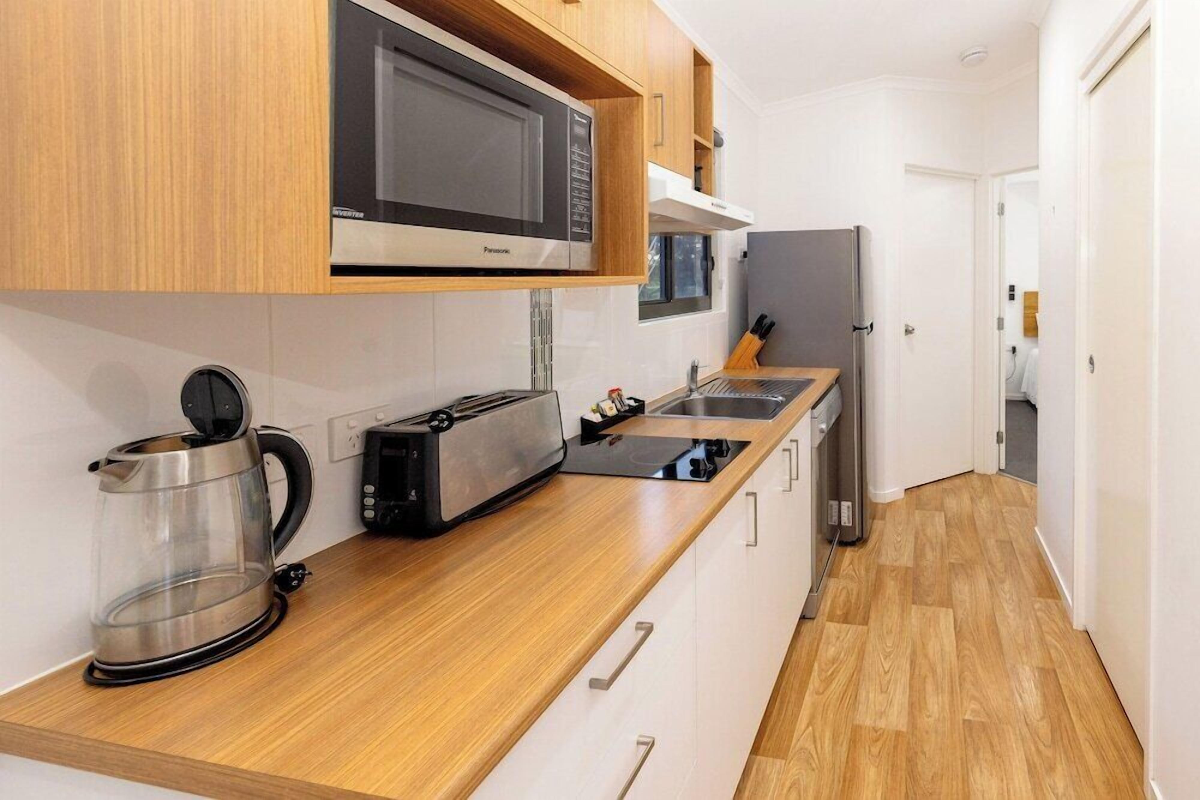 Una cocina moderna equipada con microondas, tostadora, hervidor y refrigerador.