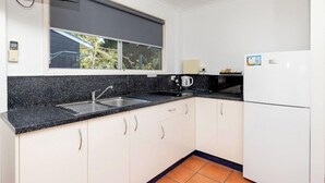 Eine Küche mit Spüle, Arbeitsplatte, Schränken, einem Fenster und einem Kühlschrank.