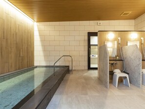 Ein modernes Badezimmer mit einer Glaskabine zur Dusche, einer Holzbalkendecke und einem gefliesten Boden.