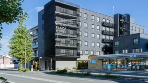 A modern hotel building with multiple floors, balconies, and a 7-Eleven convenience store on the ground level. - Kyoto Plaza Hotel Kintetsu Jujo (Kyoto)
