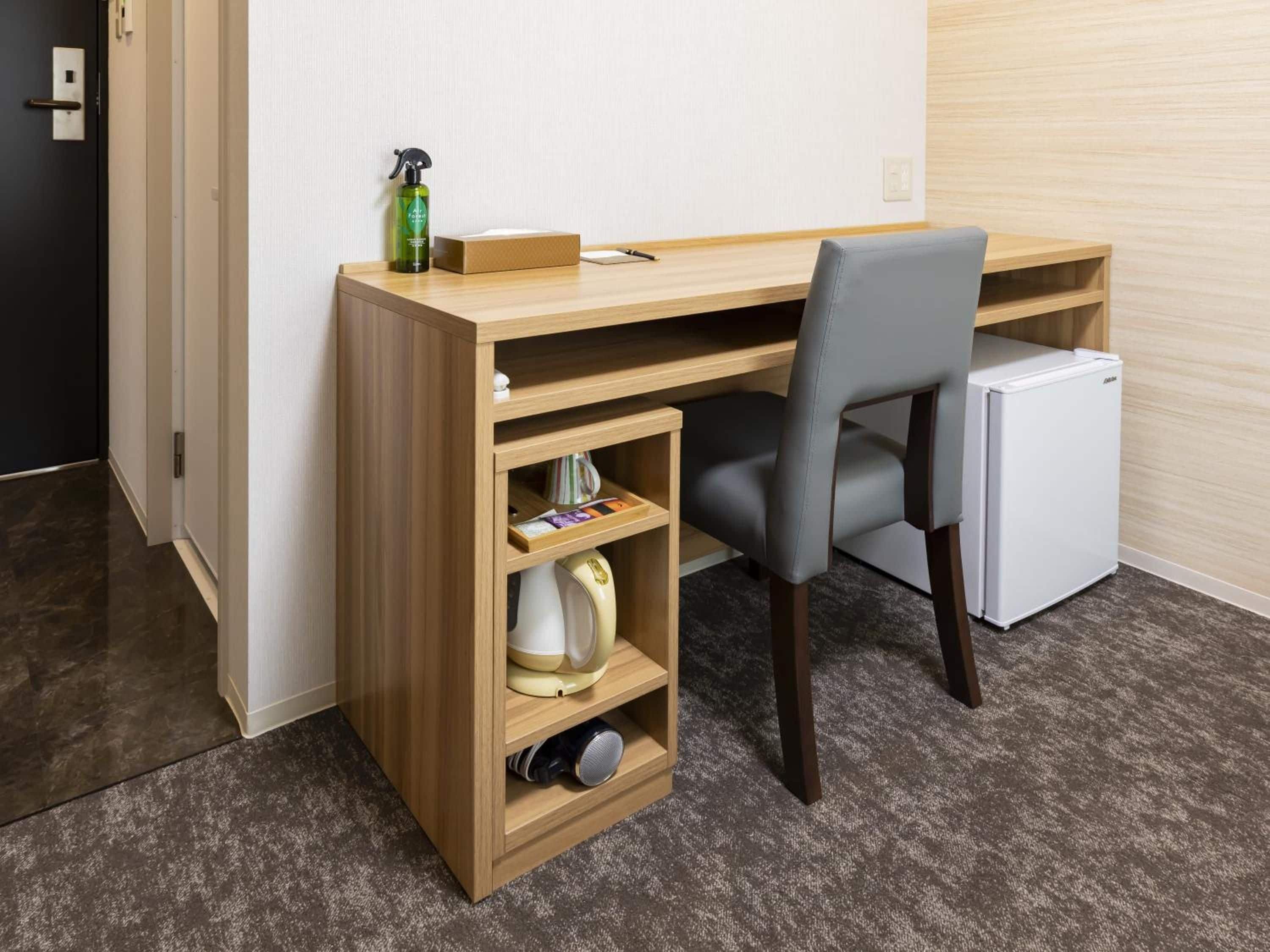 Un espacio de trabajo pequeño con escritorio, silla y un refrigerador.