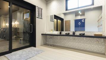 Un baño moderno con entrada de puerta de vidrio, un espejo grande y un perchero para toallas.