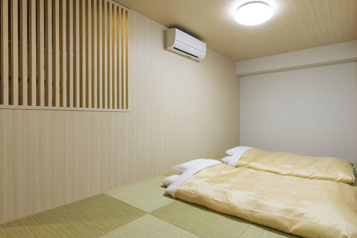 Ein Zimmer mit einem Bett, einem Vorhangfenster, einer Wandklimaanlage und einer Holzbalkendecke.