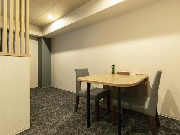 A conference room with a round table, two chairs, a small table with a bottle and tissue box, and a partition with vertical slats. - Kyoto Plaza Hotel Kintetsu Jujo (Kyoto)
