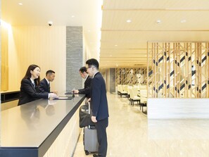 A hotel reception area with a modern design, including a reception desk, seating area, and a patterned wall. - Kyoto Plaza Hotel Kintetsu Jujo (Kyoto)