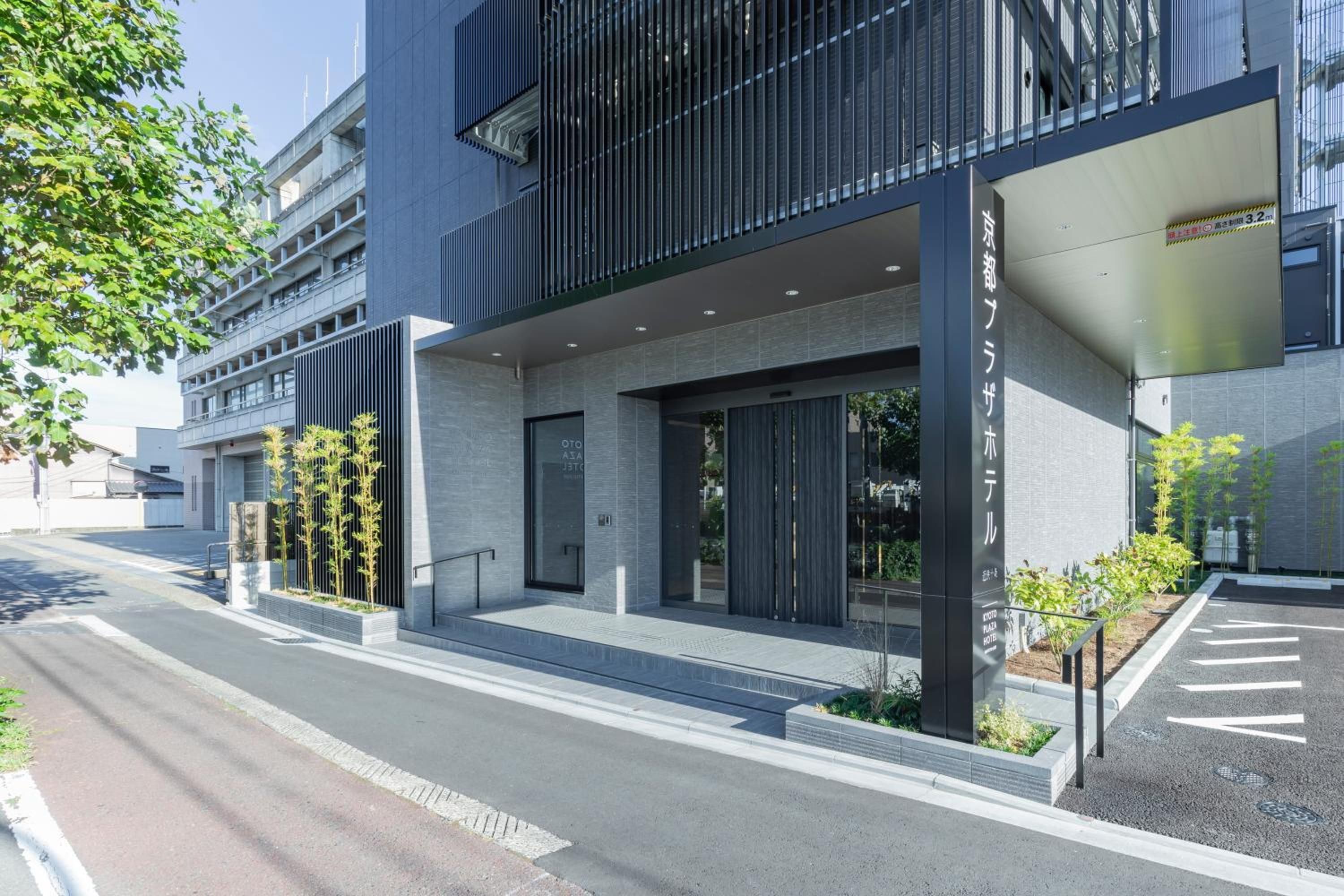 Un moderno edificio de hotel con fachada de vidrio, acceso cubierto y zona de estacionamiento.