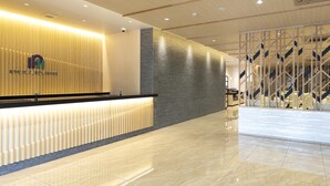 A hotel reception area with a modern design, featuring a reception desk, a logo, and a staircase in the background. - Kyoto Plaza Hotel Kintetsu Jujo (Kyoto)