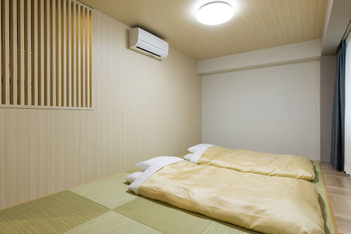 Ein Zimmer mit zwei Betten, einer Wand-Klimaanlage und einer Schiebetür.