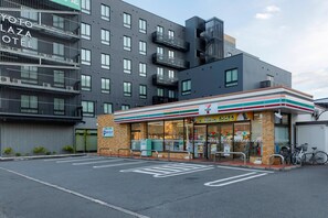 A 7-Eleven convenience store adjacent to a multi-story building with balconies. - Kyoto Plaza Hotel Kintetsu Jujo (Kyoto)