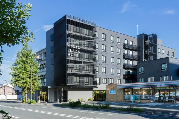 A modern hotel building with multiple floors, balconies, and a 7-Eleven convenience store on the ground level. - Kyoto Plaza Hotel Kintetsu Jujo (Kyoto)