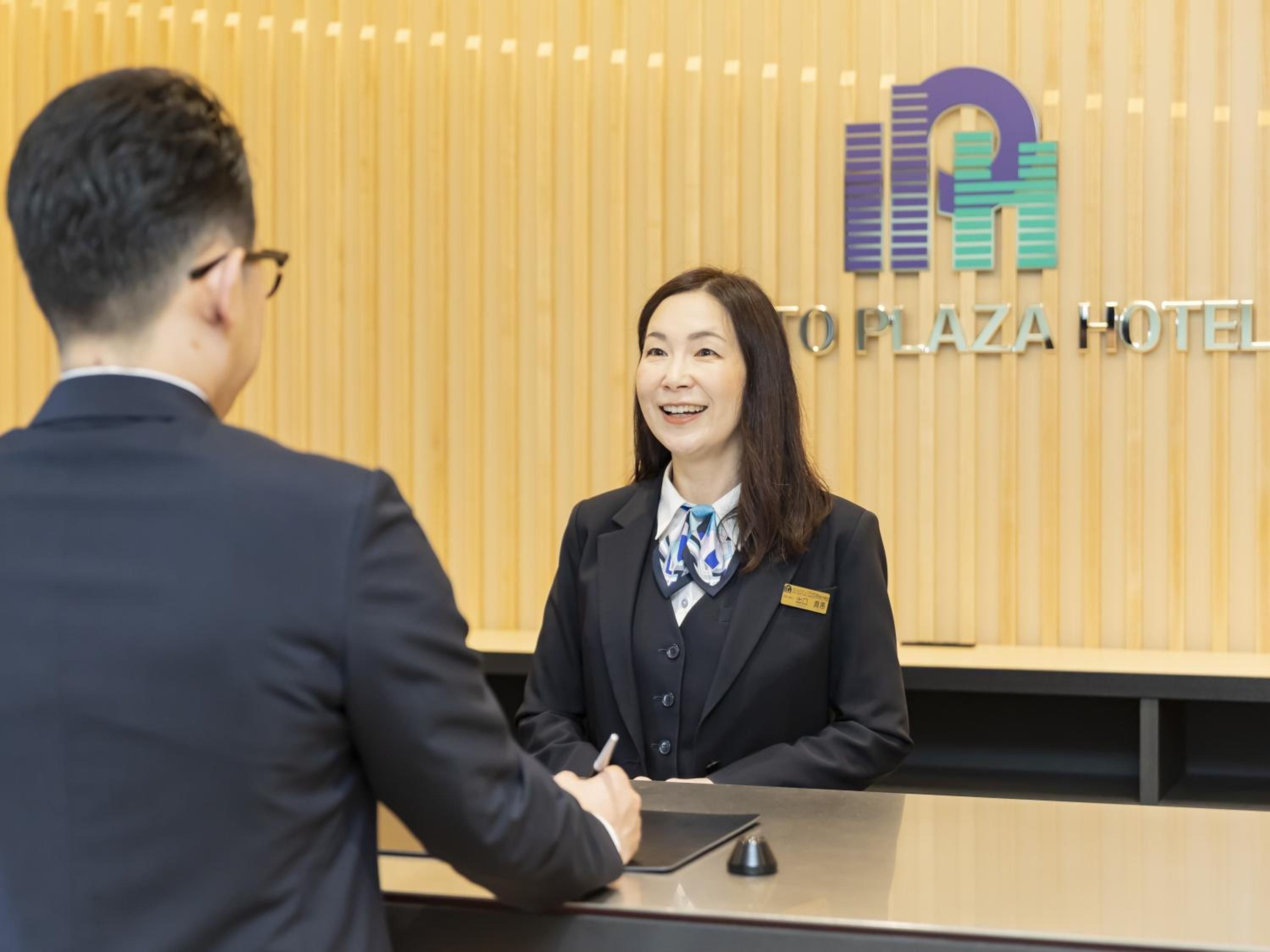 Mostrador de recepción de hotel con fondo de madera y logotipo de 'O'PLAZA HOTEL'.