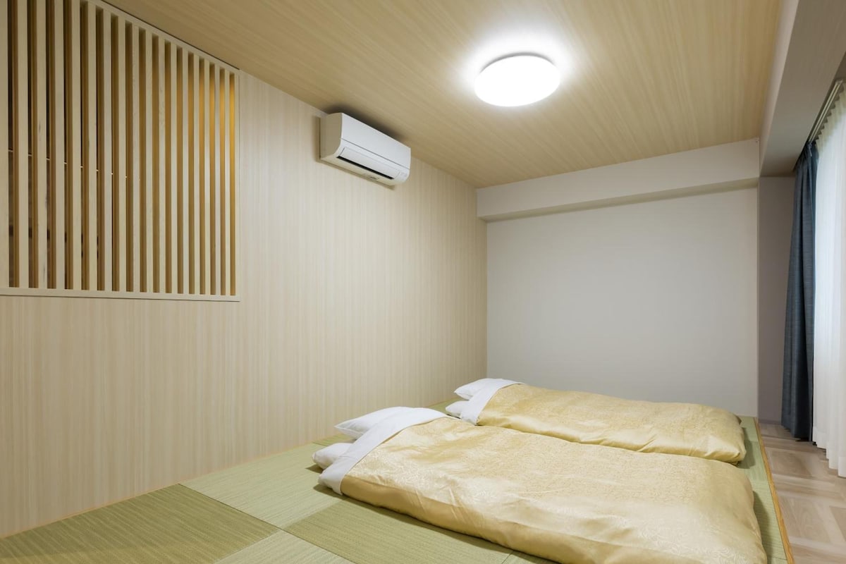 A room with a bed, a wall-mounted air conditioner, and a ceiling light.