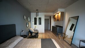 A modern bedroom with a bed, bedside table, lamp, chair, and a small desk with a vase. - Howard Johnson by Wyndham Buenos Aires La Boca Undici (Buenos Aires)