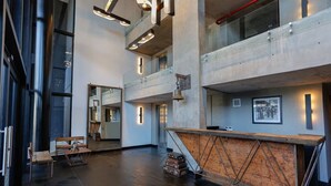 A spacious lobby with high ceilings, a central wooden reception desk, and a mezzanine level. - Howard Johnson by Wyndham Buenos Aires La Boca Undici (Buenos Aires)