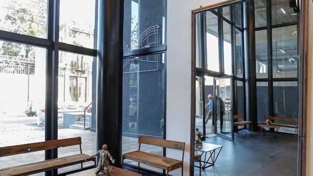 A modern interior with large windows, wooden benches, and a glass partition. - Howard Johnson by Wyndham Buenos Aires La Boca Undici (Buenos Aires)