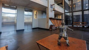 A spacious lobby with a large glass wall, a statue on a table, and a high ceiling with exposed beams. - Howard Johnson by Wyndham Buenos Aires La Boca Undici (Buenos Aires)