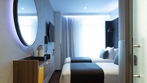 Camera d'albergo moderna con un letto grande, un comodino con TV a schermo piatto, uno specchio e un armadio.